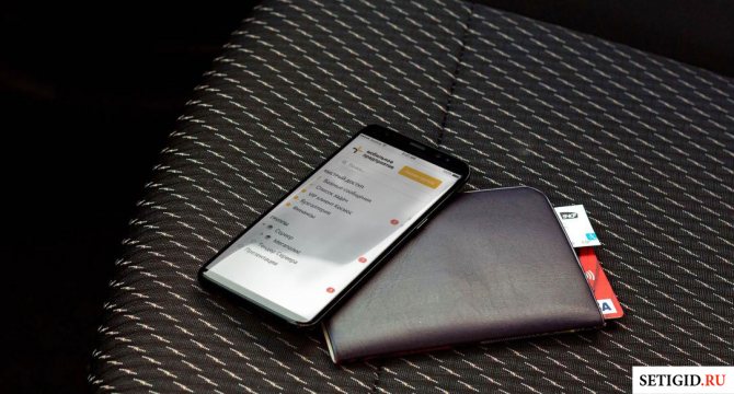 Мобильный телефон и кошелек на кресле автомобиля
